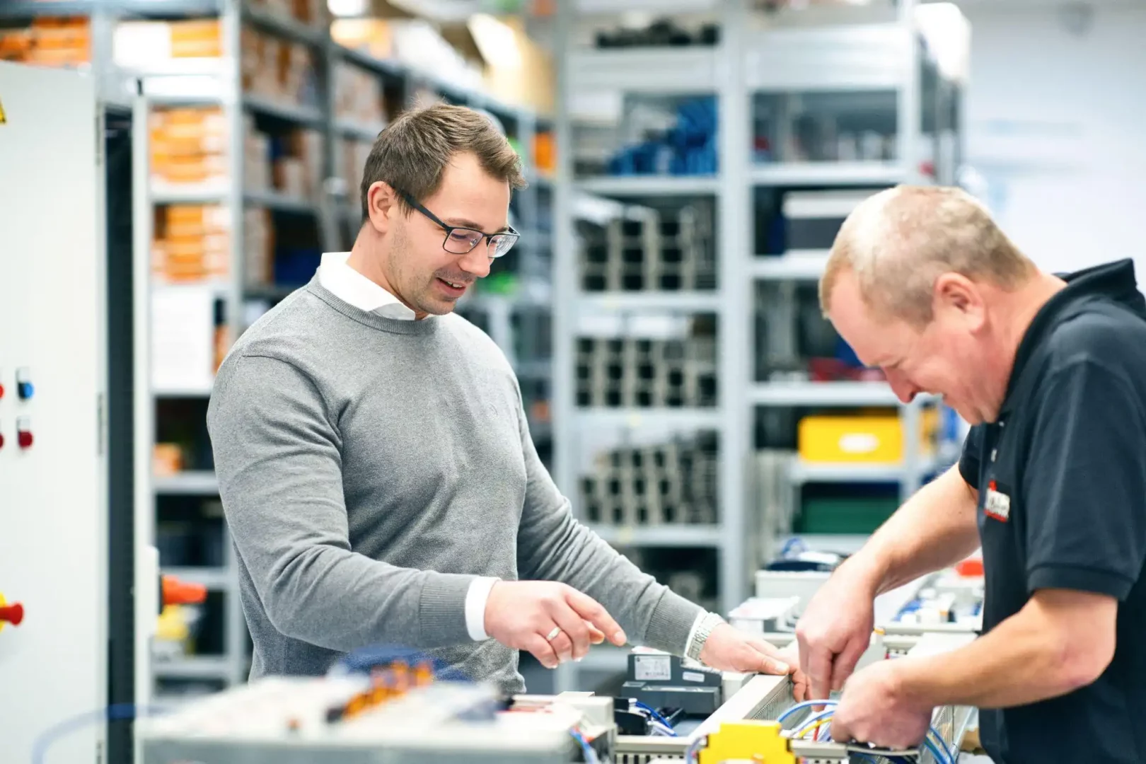 Zwei Techniker arbeiten an Maschinensicherheitssystemen in einer Werkstatt.