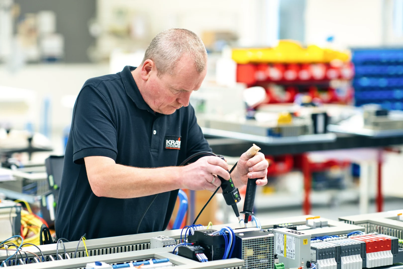 An experienced technician is installing components in a control cabinet for a custom machine