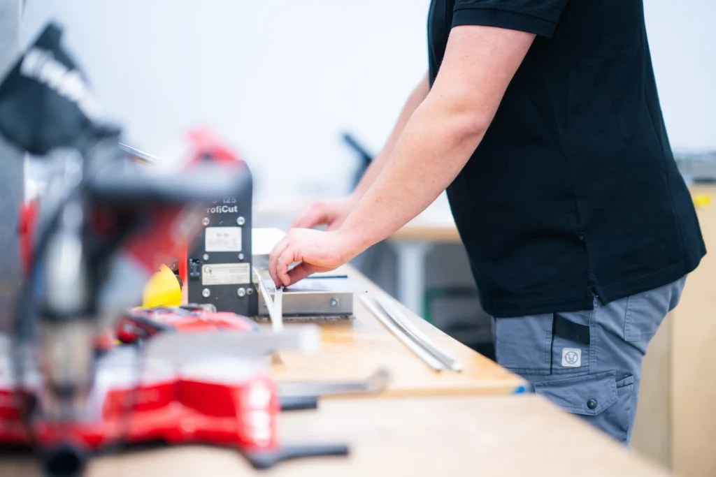 Mitarbeiter montiert Bauteile an einer Werkbank – sorgfältige Handarbeit als Teil der Schaltschrankfertigung.
