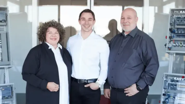 Drei Mitarbeiter von Krayer Systemtechnik im Büro, lächelnd und professionell.
