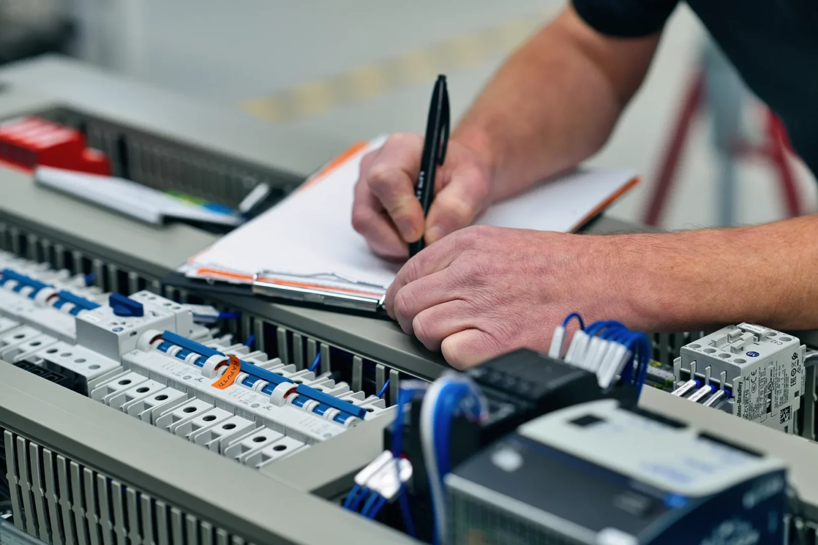 Produktionshelfer bei Krayer Systemtechnik mit Notizblock und Werkzeugen.
