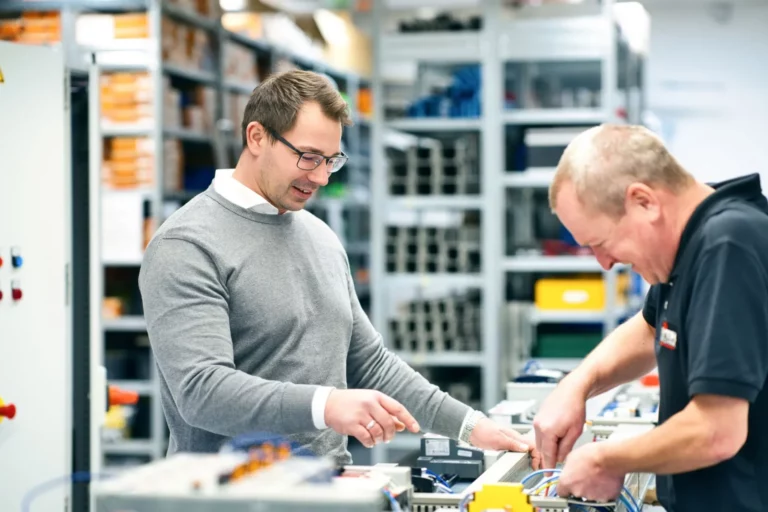 Zwei Männer bei Elektroarbeiten in einer Werkstatt.