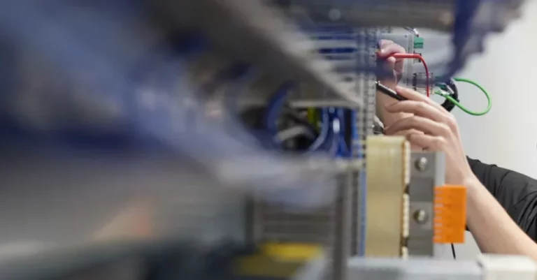 Elektriker arbeitet an einem CSA-Schrank mit Steuerungskomponenten.